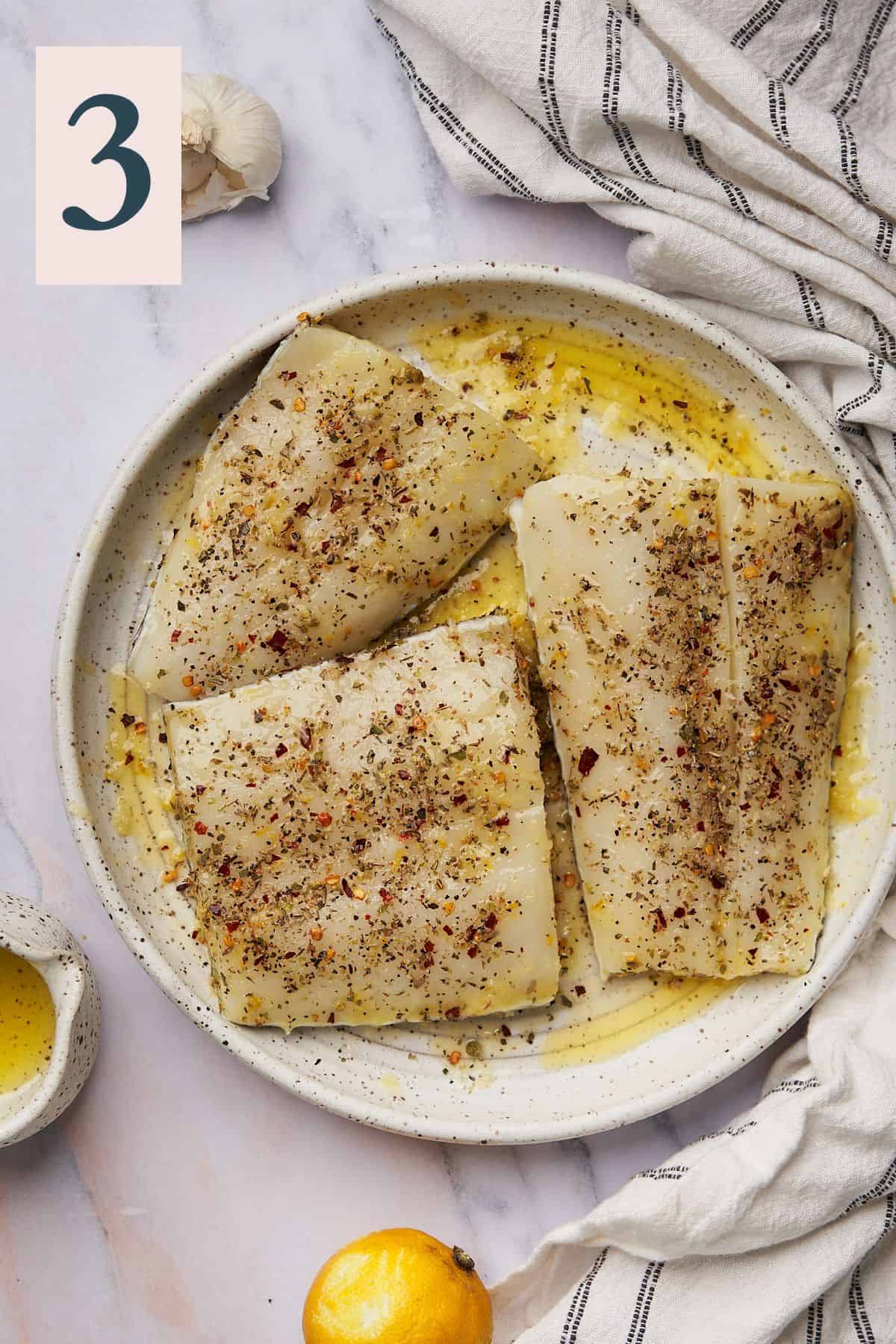 chilean sea bass fillets seasoned on a plate and drizzled with butter and olive oil. 