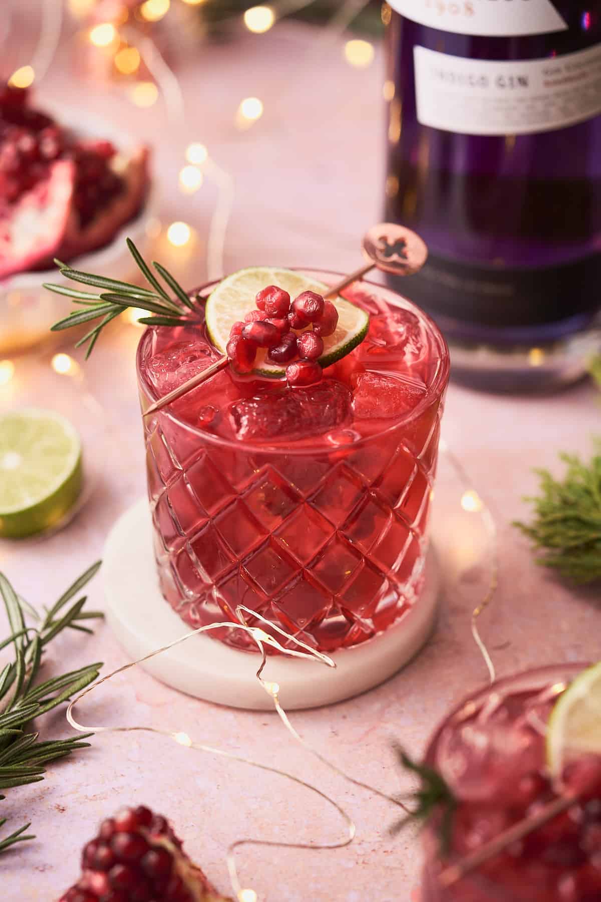 Pomegranate gin cocktail with limes, rosemary, and empress gin.