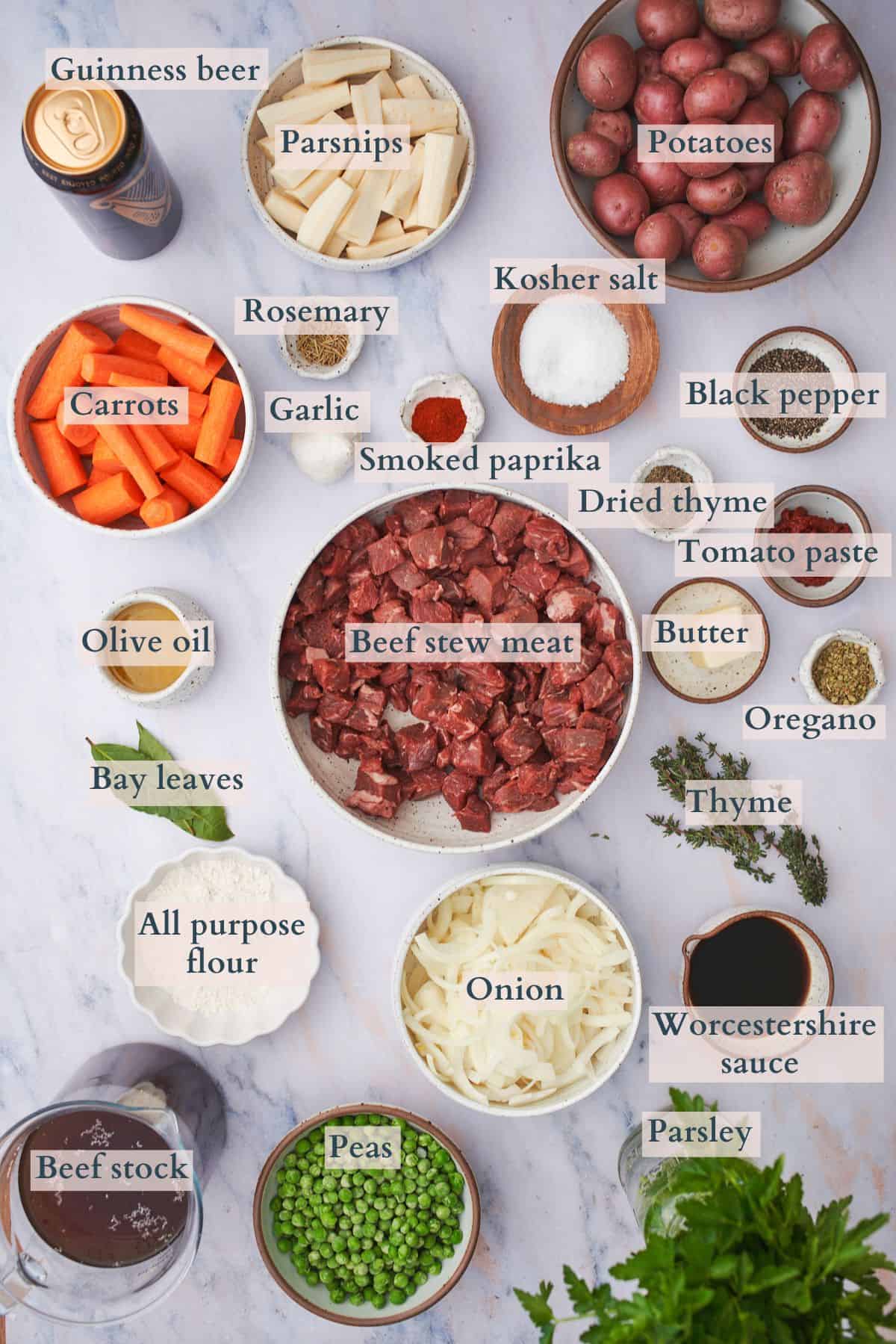 ingredients to make slow cooker irish beef stew laid out on plates and in bowls, labeled to denote each ingredient.