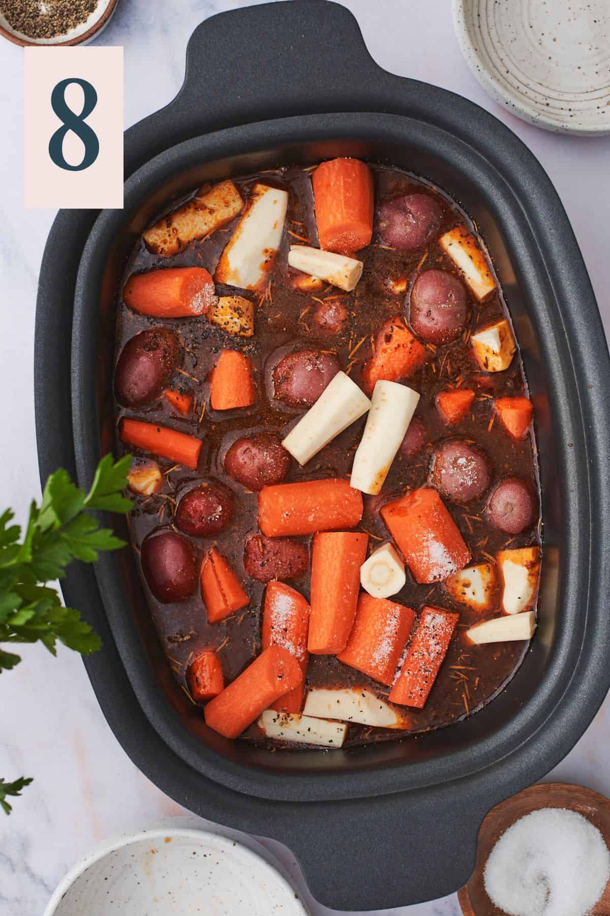 beef stock in a slow cooker with parsnips, carrots, and red potatoes.