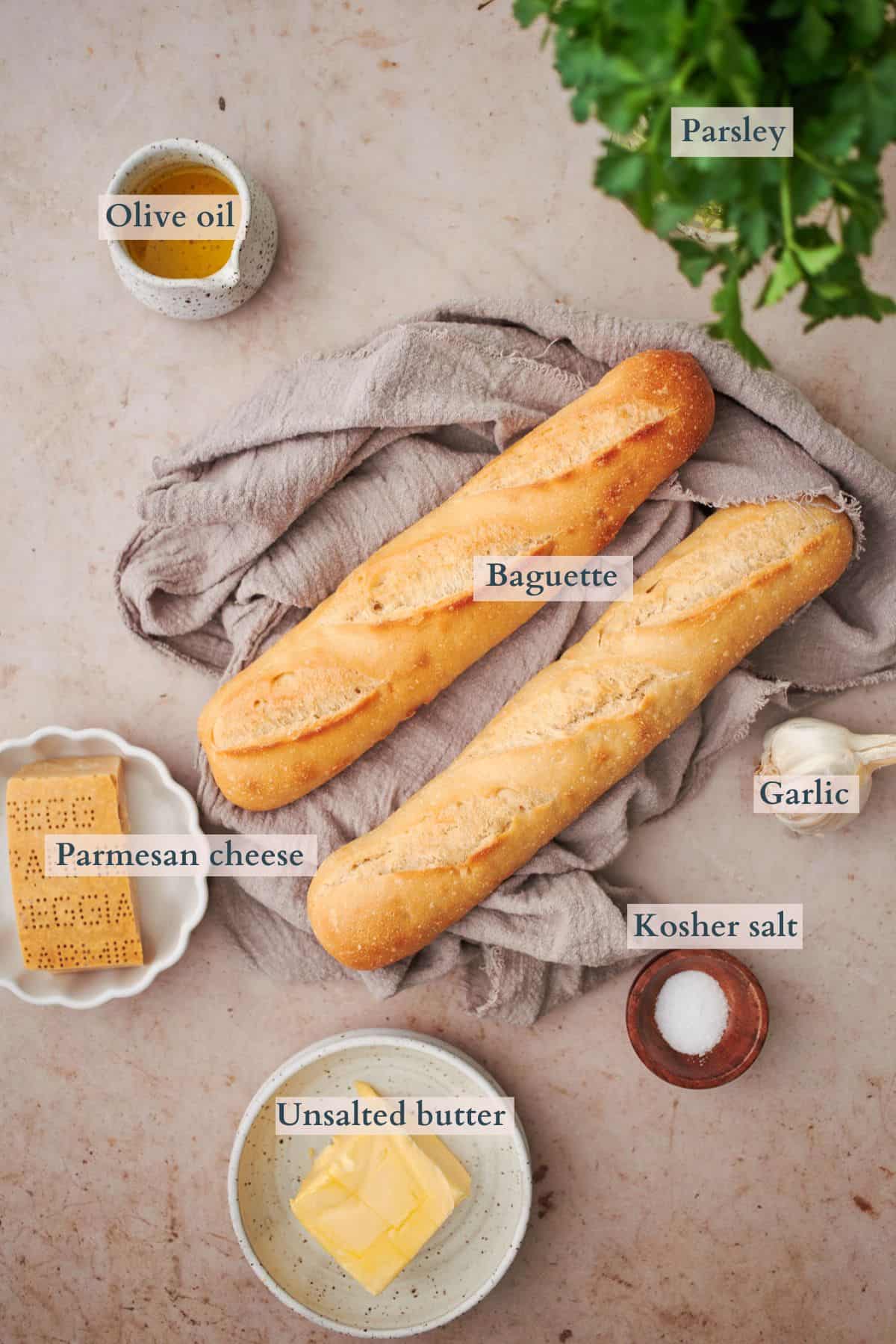 ingredients to make garlic bread laid out in small bowls and labeled to denote each ingredient.