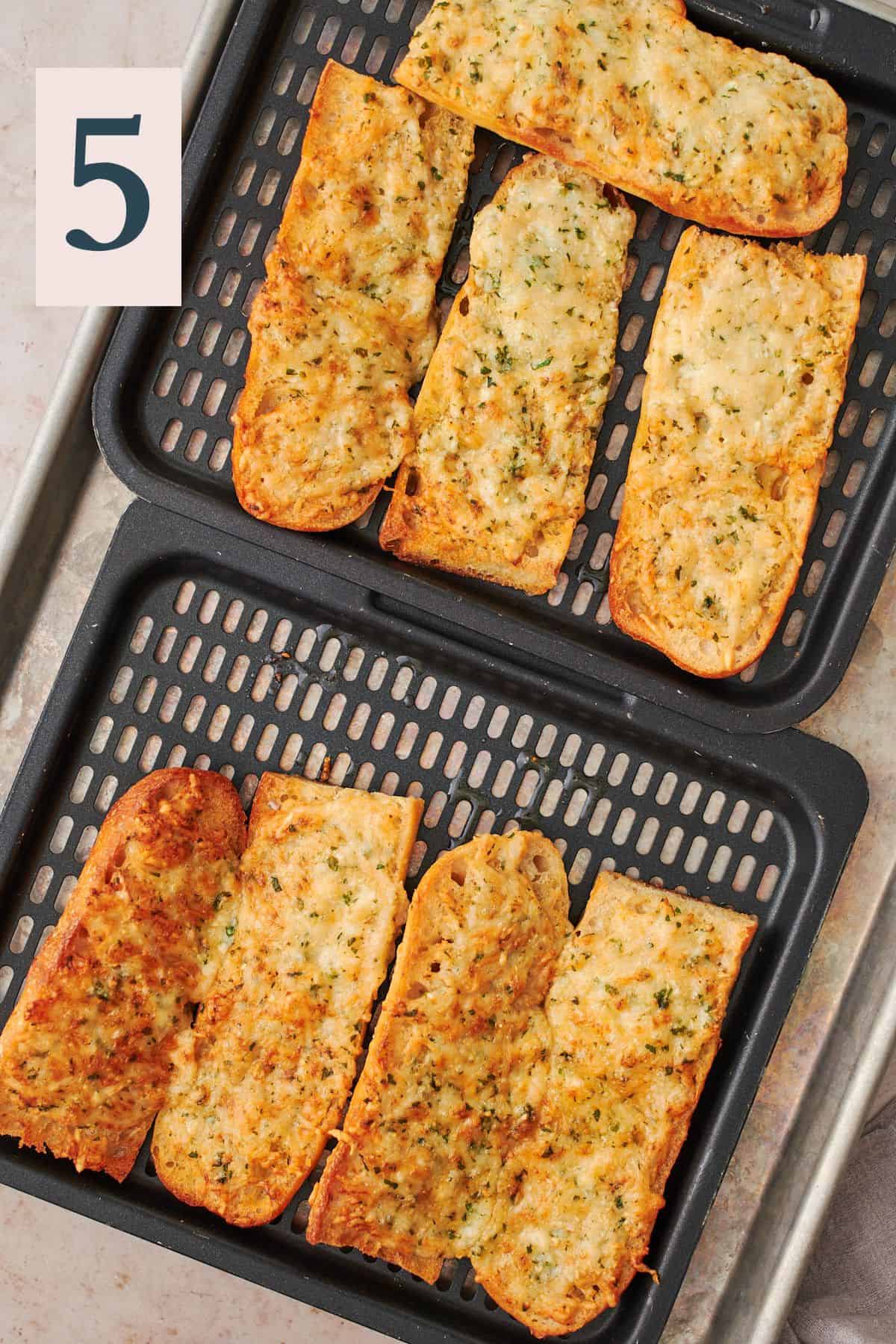 baked garlic bread slices on air fryer trays. 