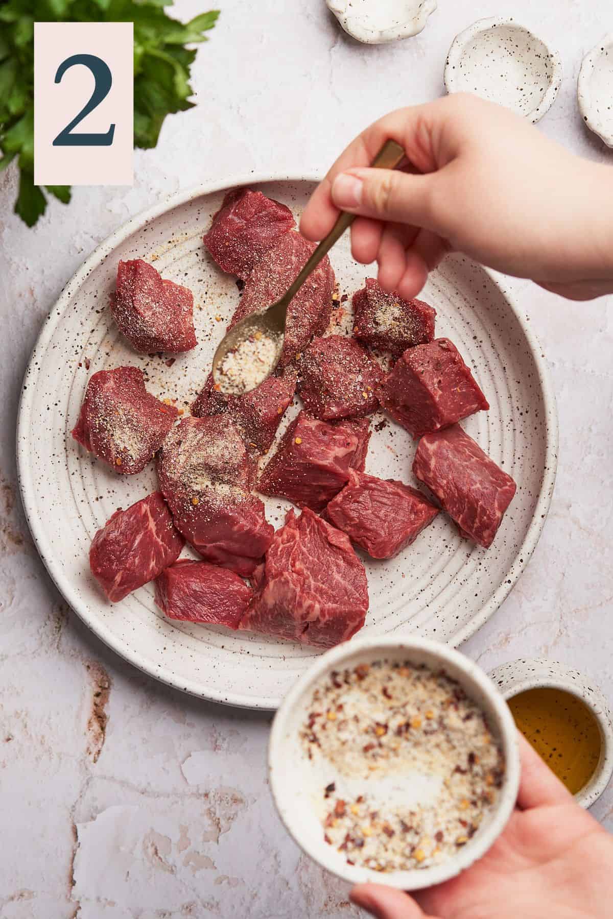 seasoning steak with spice blends evenly with a spoon.