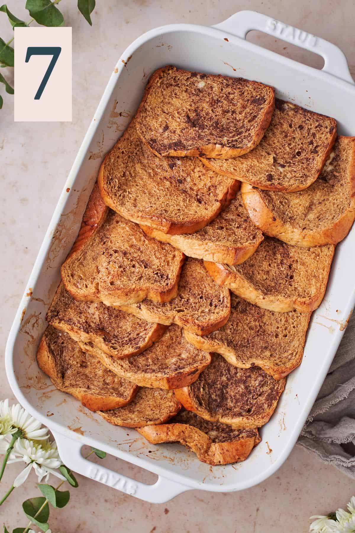 baked brioche french toast slices layered in a baking dish. 