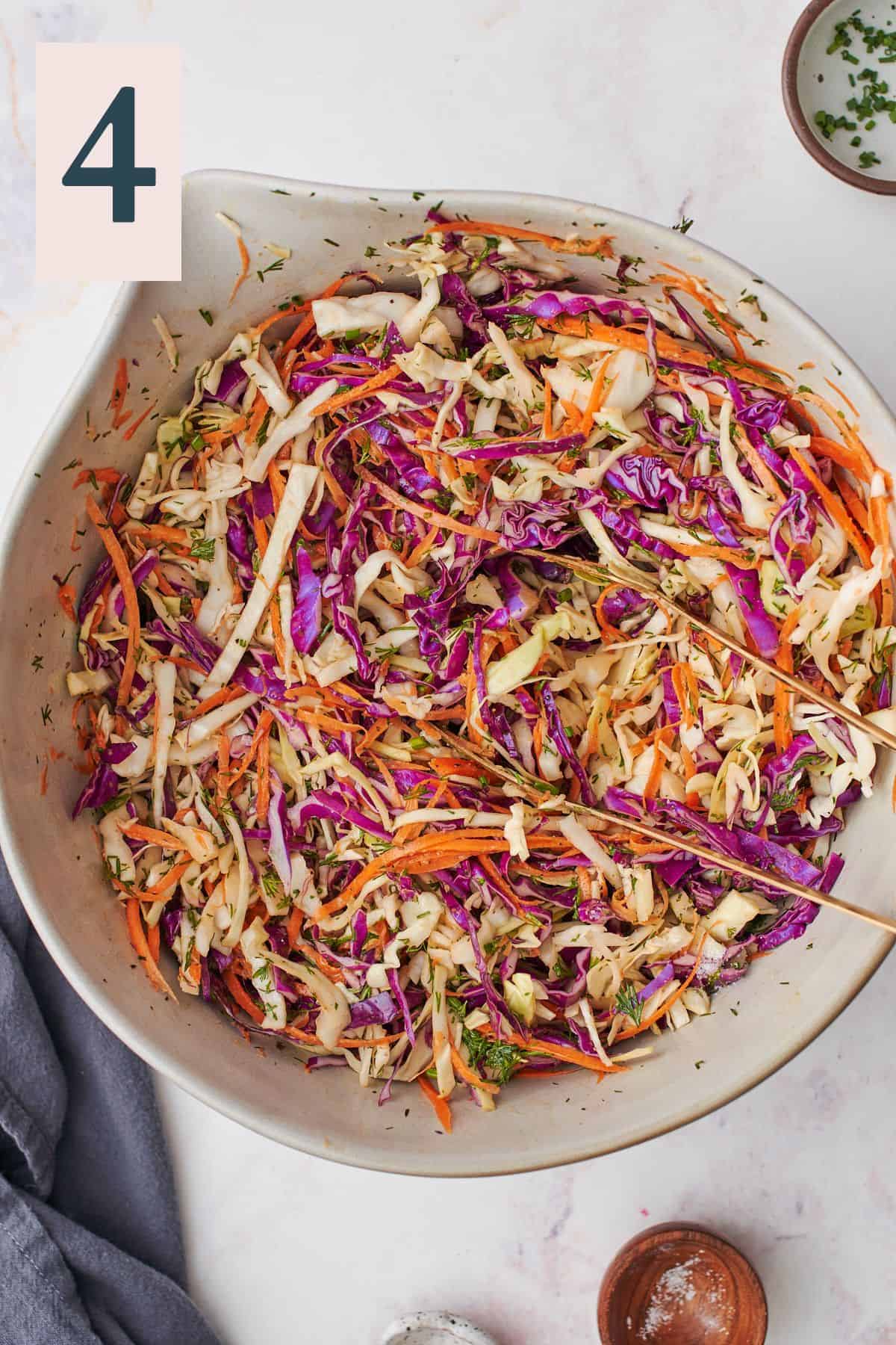 Cabbage and carrot salad tossed in a large bowl. 