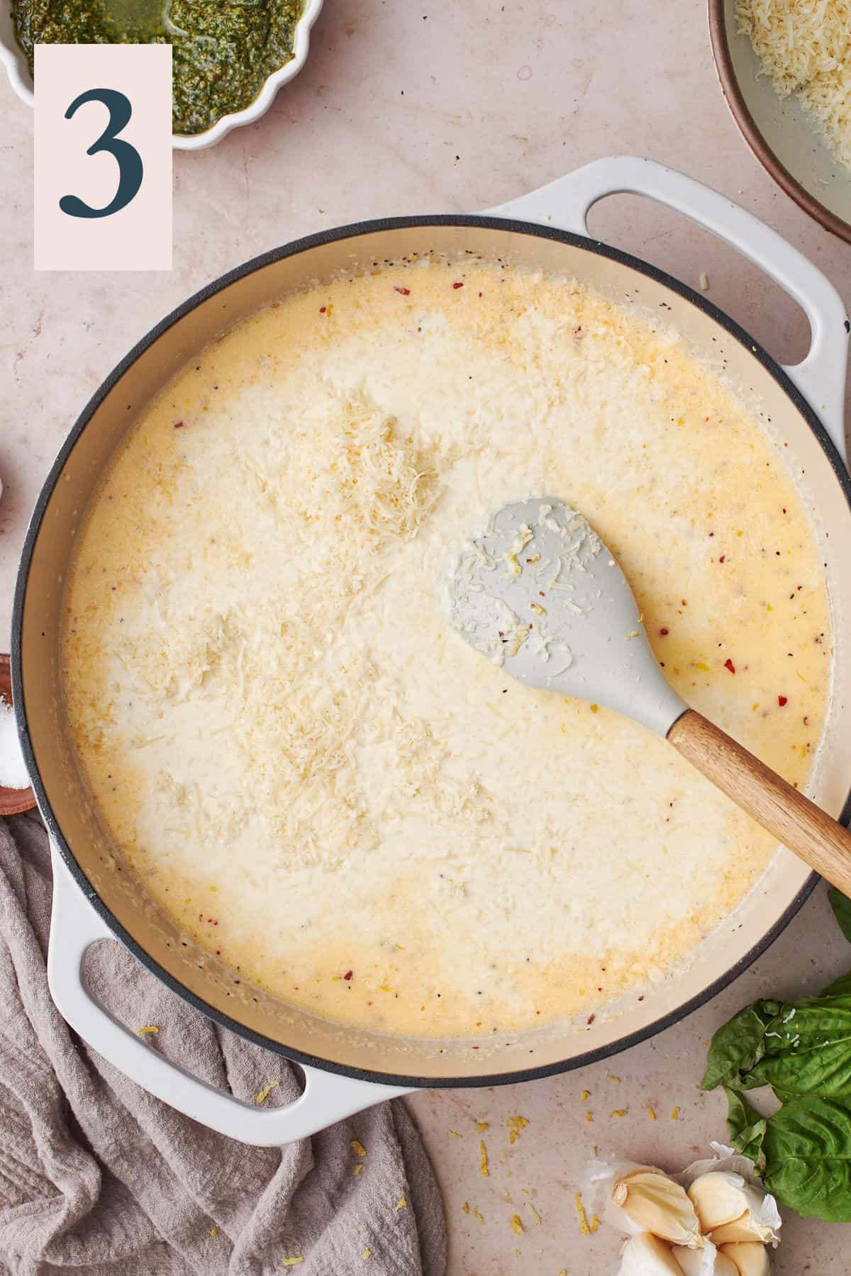 parmesan cheese being added to a cream sauce in a skillet. 