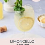 Limoncello Spritz surrounding by limoncello, lemons, another cocktail, and garnished with mint.