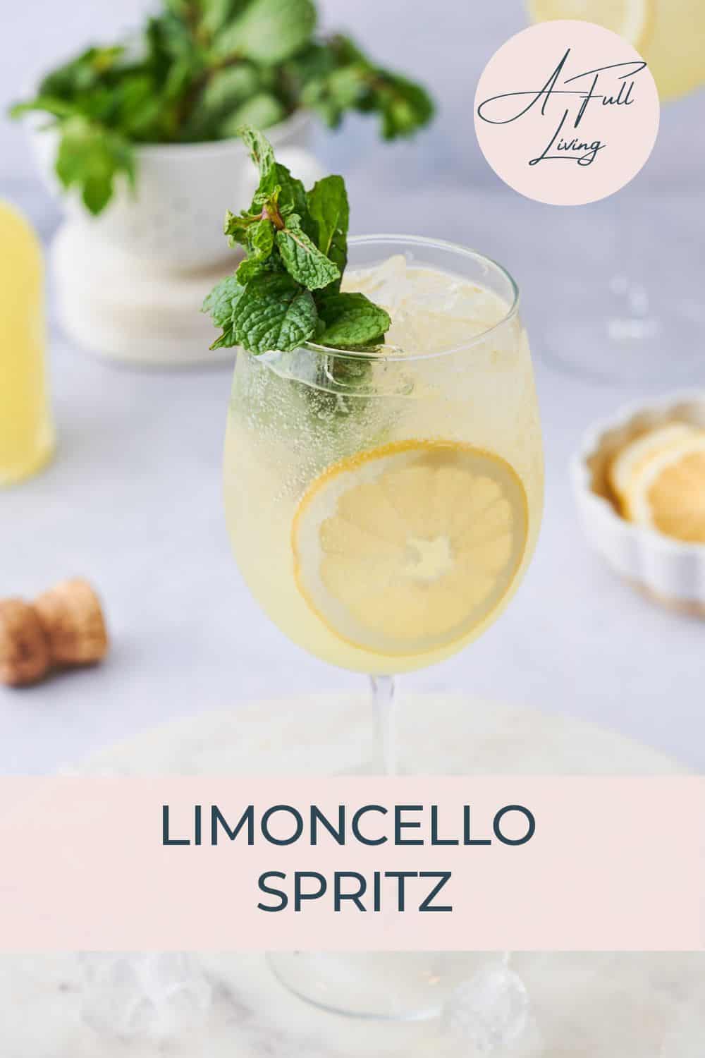 Limoncello Spritz surrounding by limoncello, lemons, another cocktail, and garnished with mint.