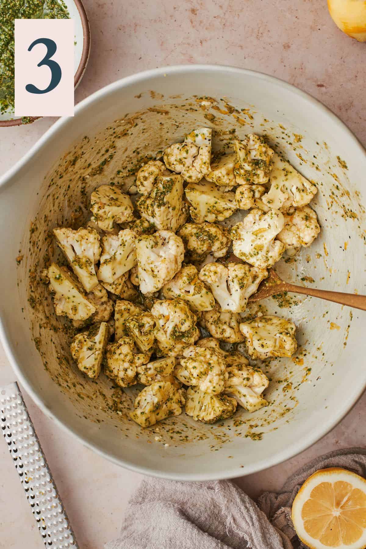 cauliflower florets tossed in pesto sauce in a large bow. 