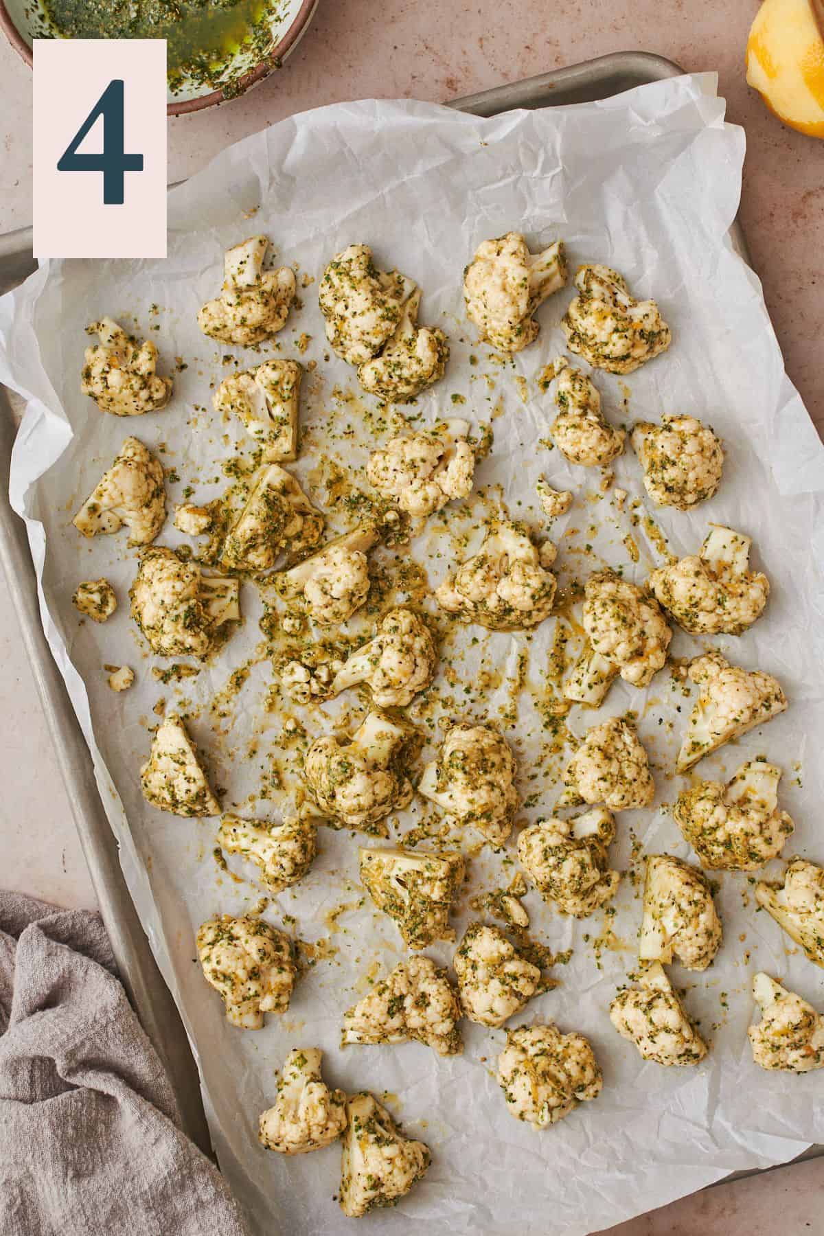 pesto coated cauliflower on a parchment lined baking sheet.