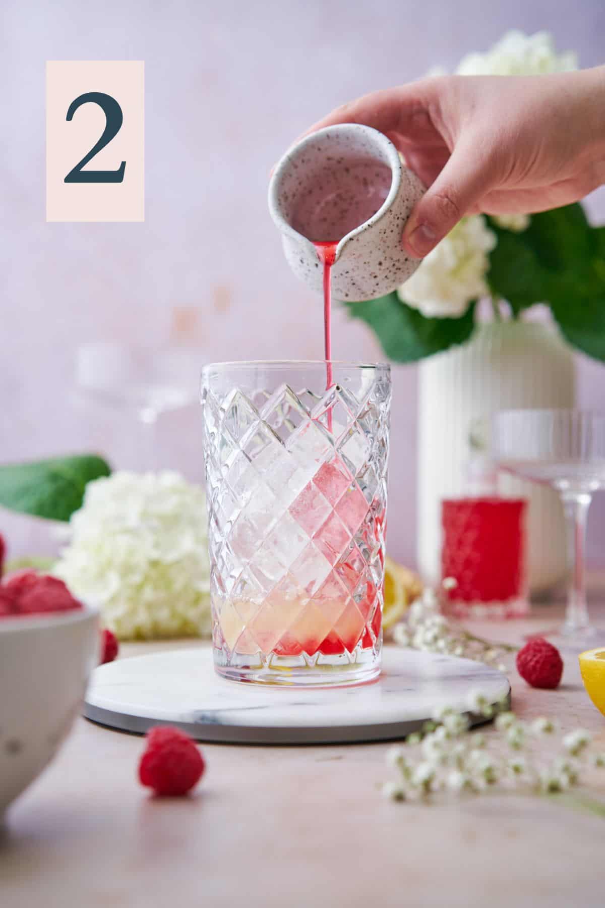 hand pouring raspberry simple syrup into a cocktail shaker with ice and lime juice. 