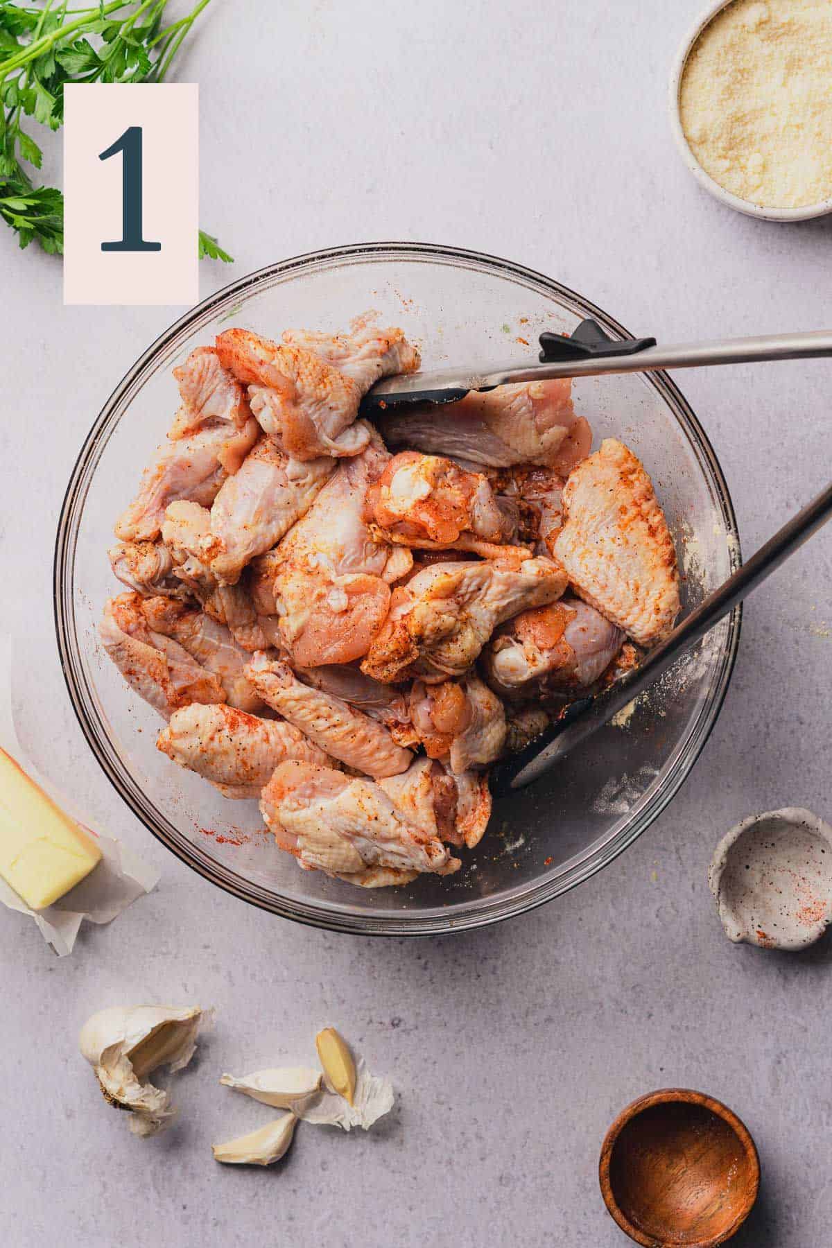 Split chicken wings tossed in a large bowl with spices and salt.