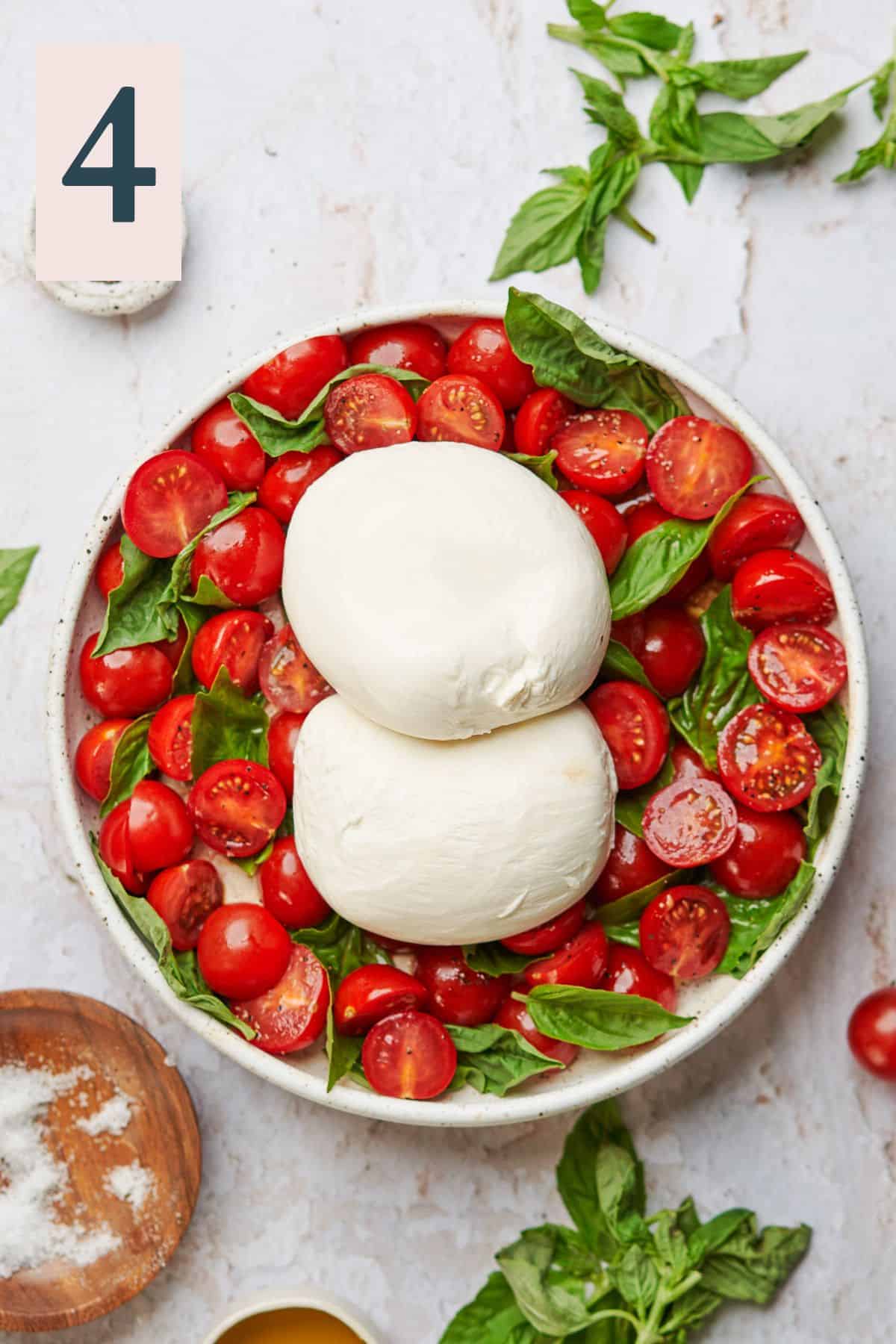 Basil placed in between cherry tomatoes and topped with warm burrata cheese.