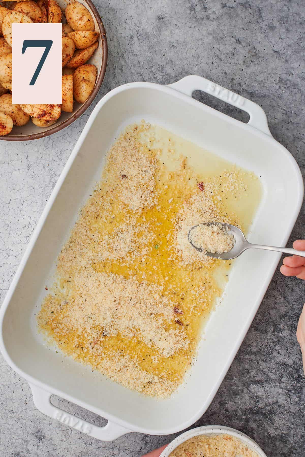 hand sprinkling parmesan cheese mixture into the bottom of a baking dish with butter and olive oil. 