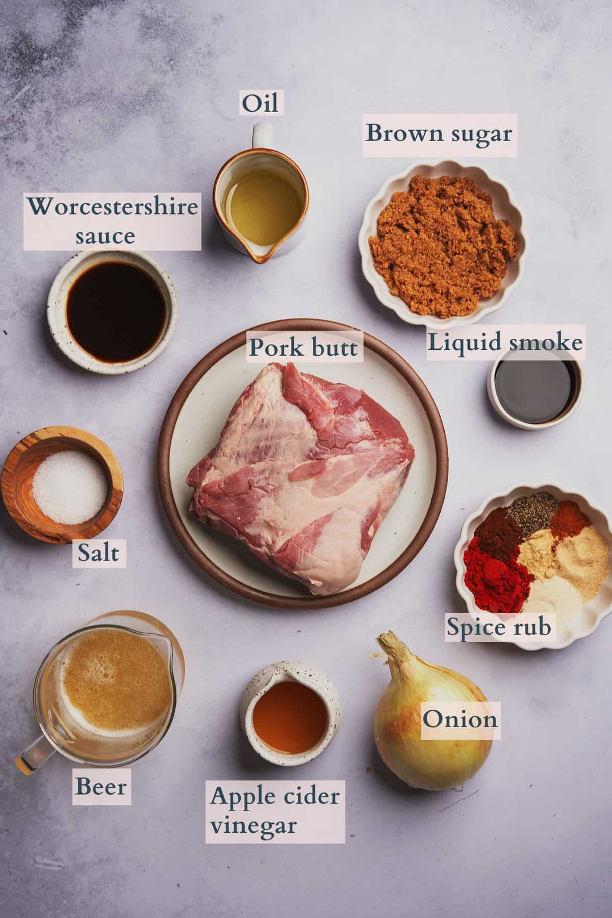 dutch oven pulled pork ingredients laid out in small bowls, with text overlaying to denote pork butt, spices, onion, apple cider vinegar, beer, salt, Worcestershire sauce, oil, brown sugar, and liquid smoke. 