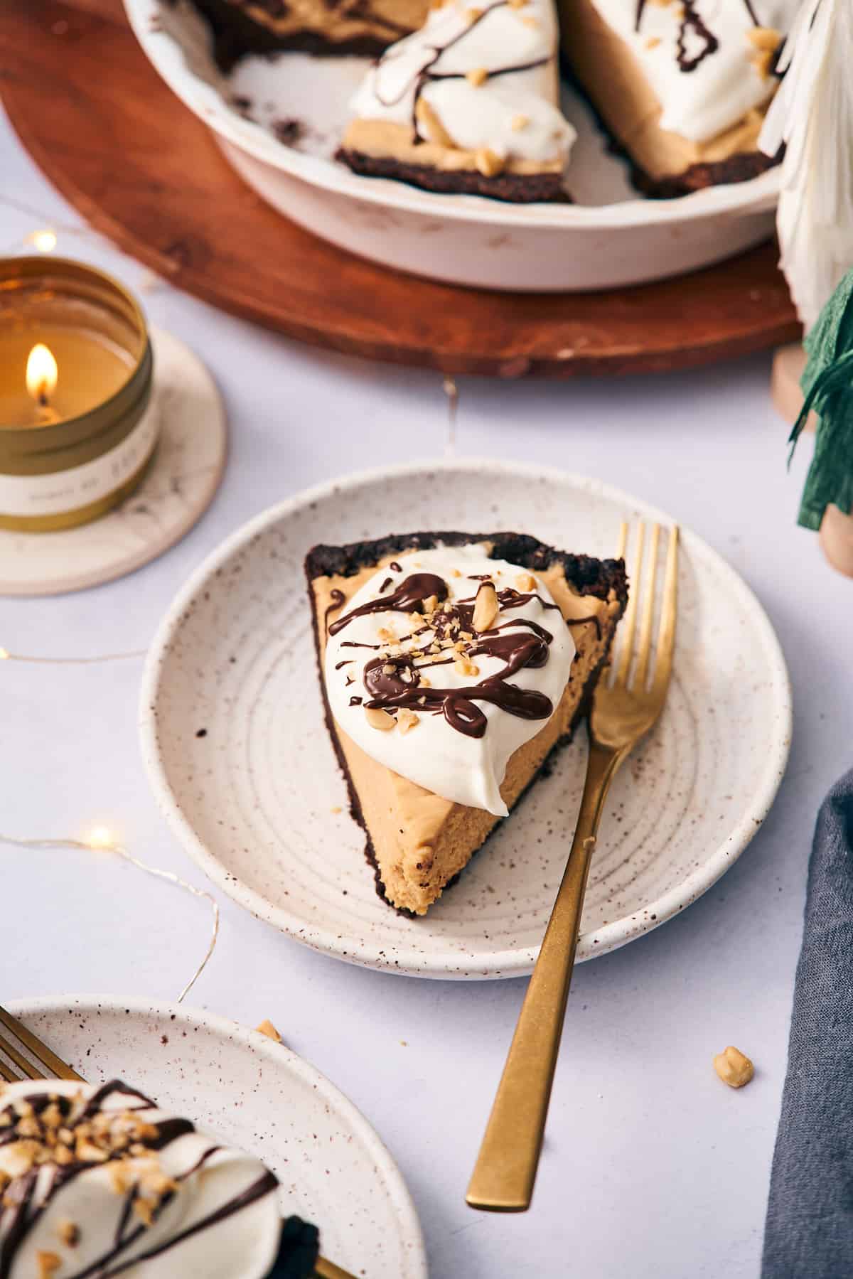 slice of keto peanut butter pie on a plate with a gold fork, and a lit candle in the background. 