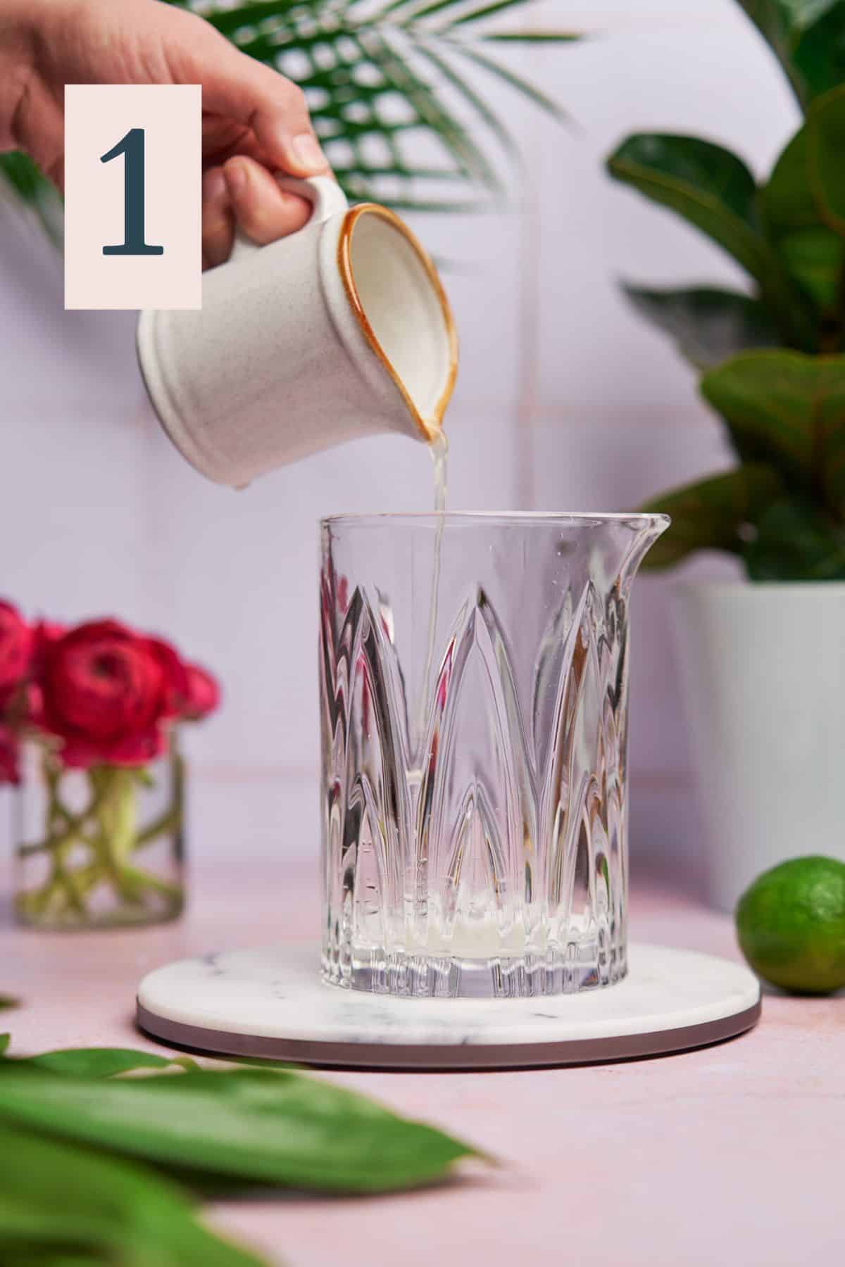 Pouring lime juice into a cocktail mixing glass.