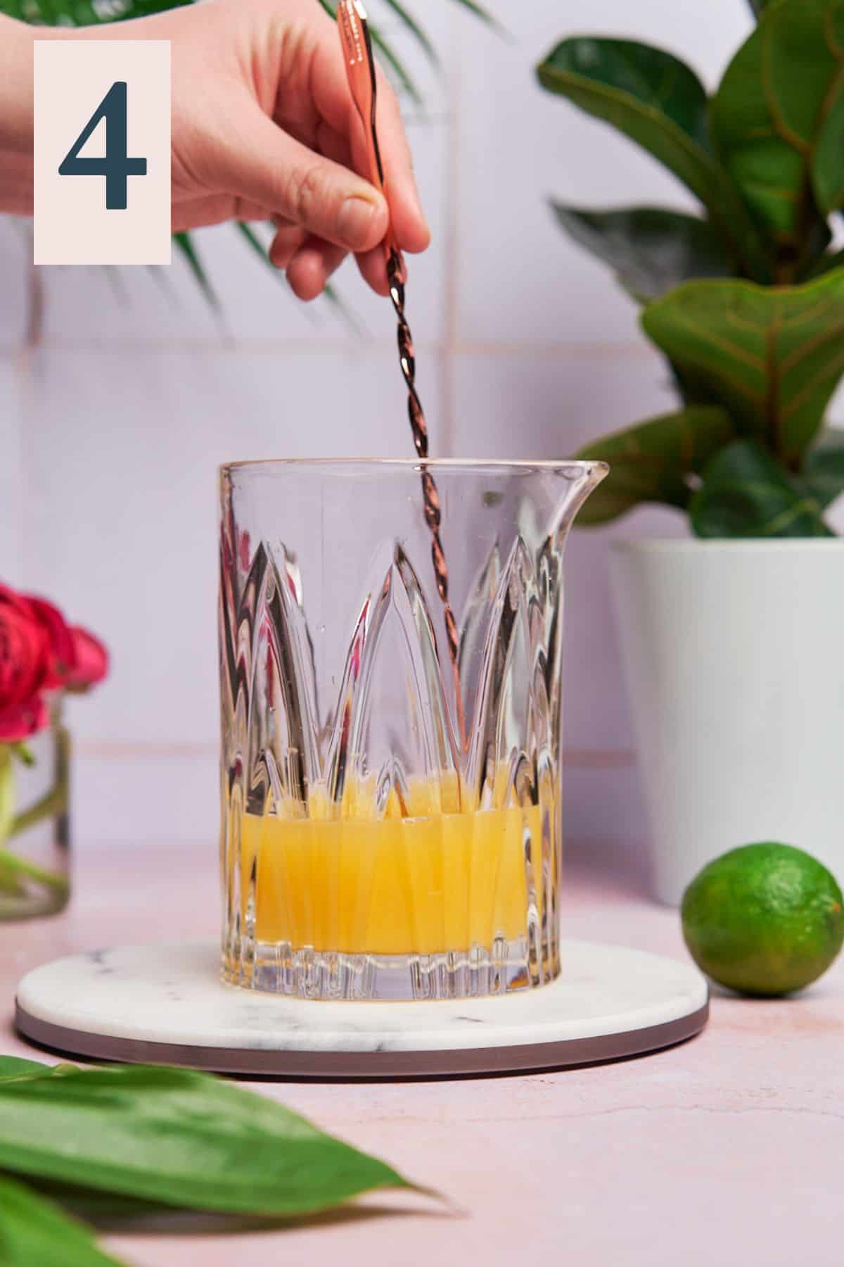 Pineapple mimosa mixture being stirred gently in a glass.
