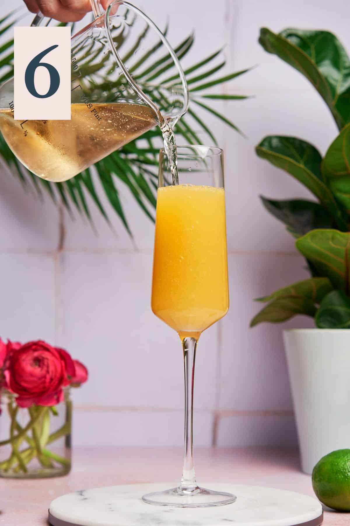 Pouring champagne into pineapple mimosa mixture.