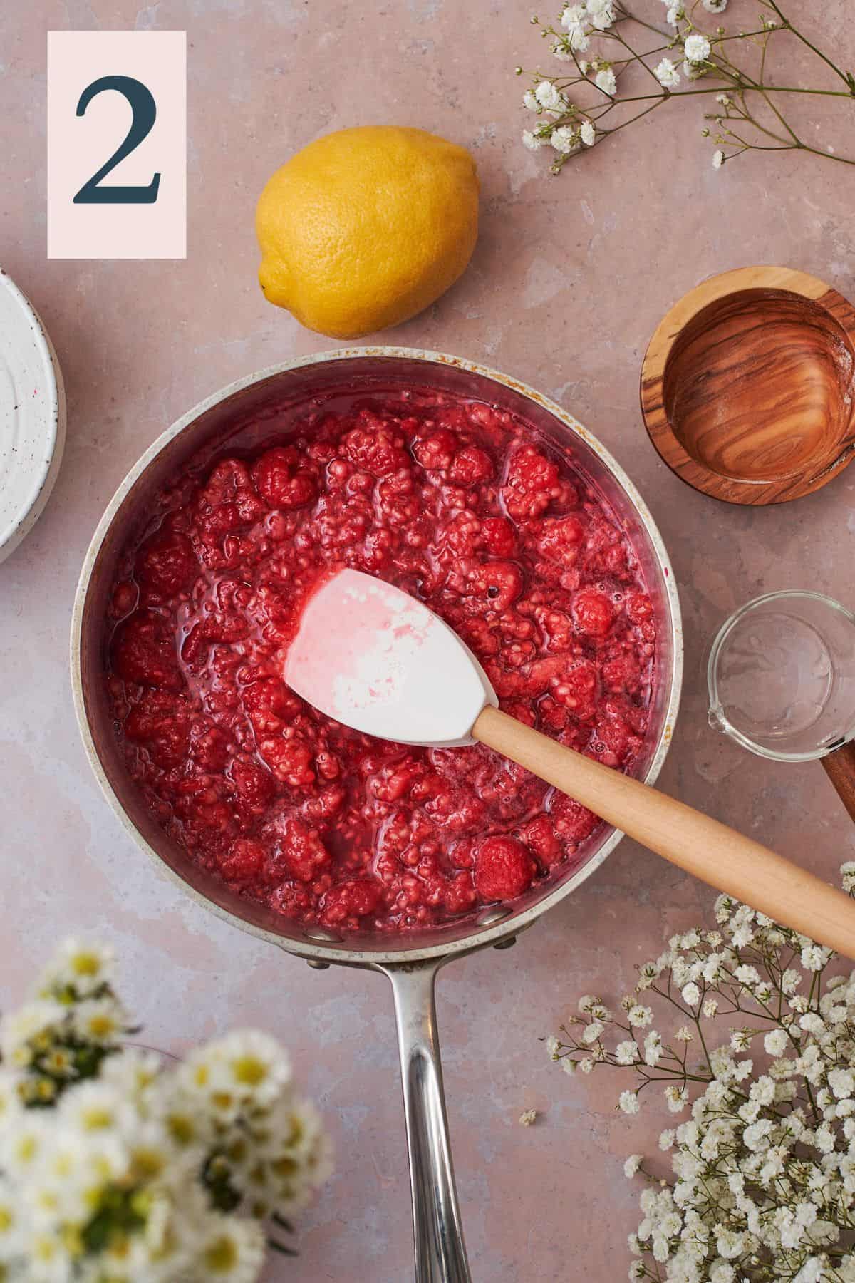 raspberries in a saucepan that have begun to break down into a sauce. 