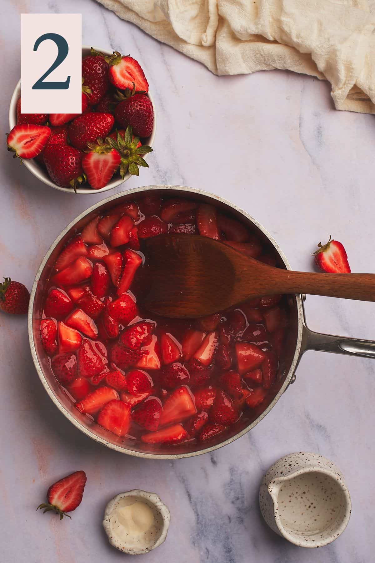 Strawberry mixture releasing liquid in a small pot, simmering slowly.