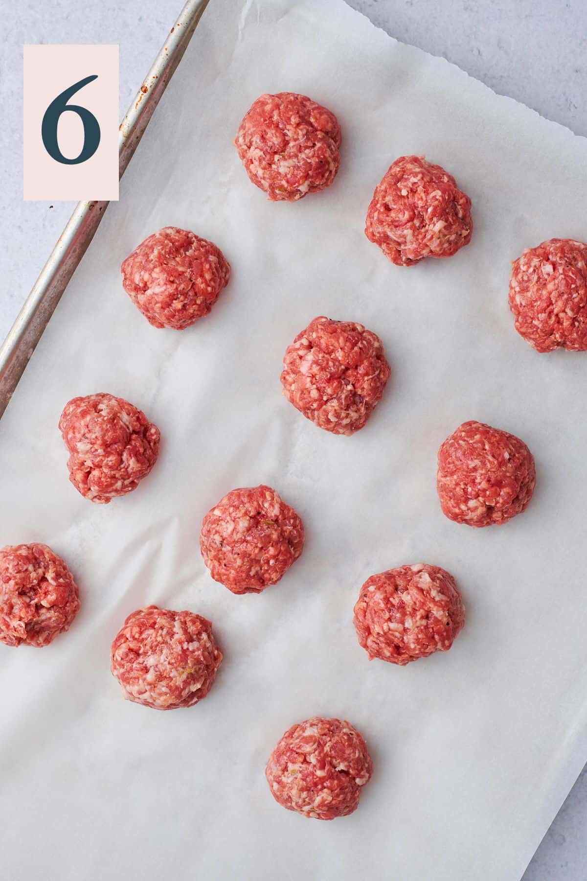 raw burger patties on a baking sheet lined with parchment.