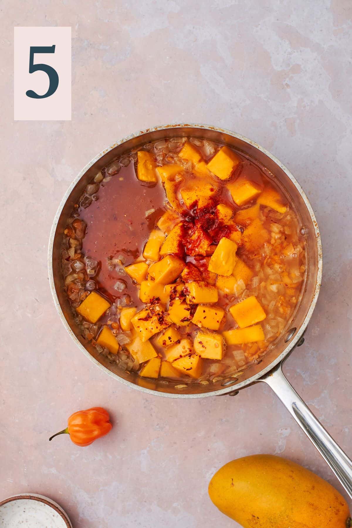 mango with liquids and honey in a saucepan with other ingredients and spices. 