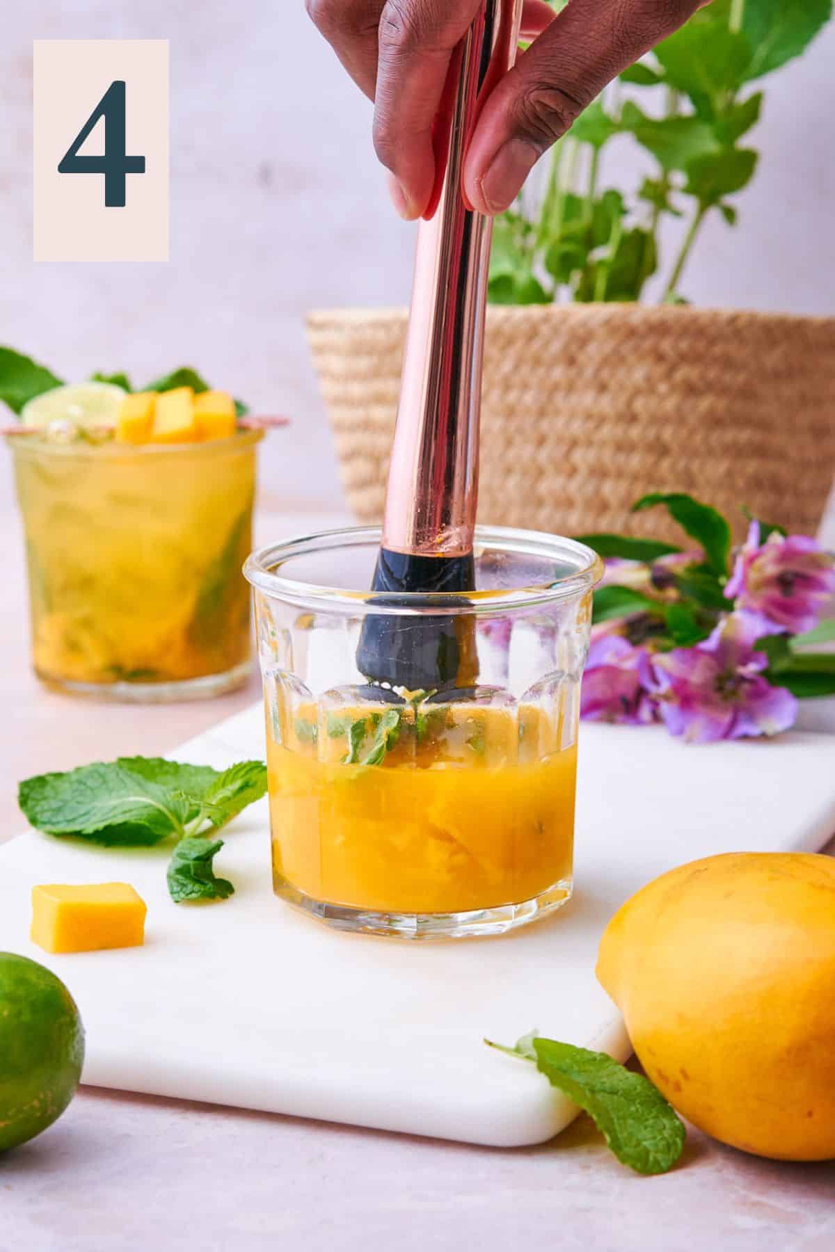 Muddling the mangos, mint leaves, and other ingredients until well incorporated into the cocktail.