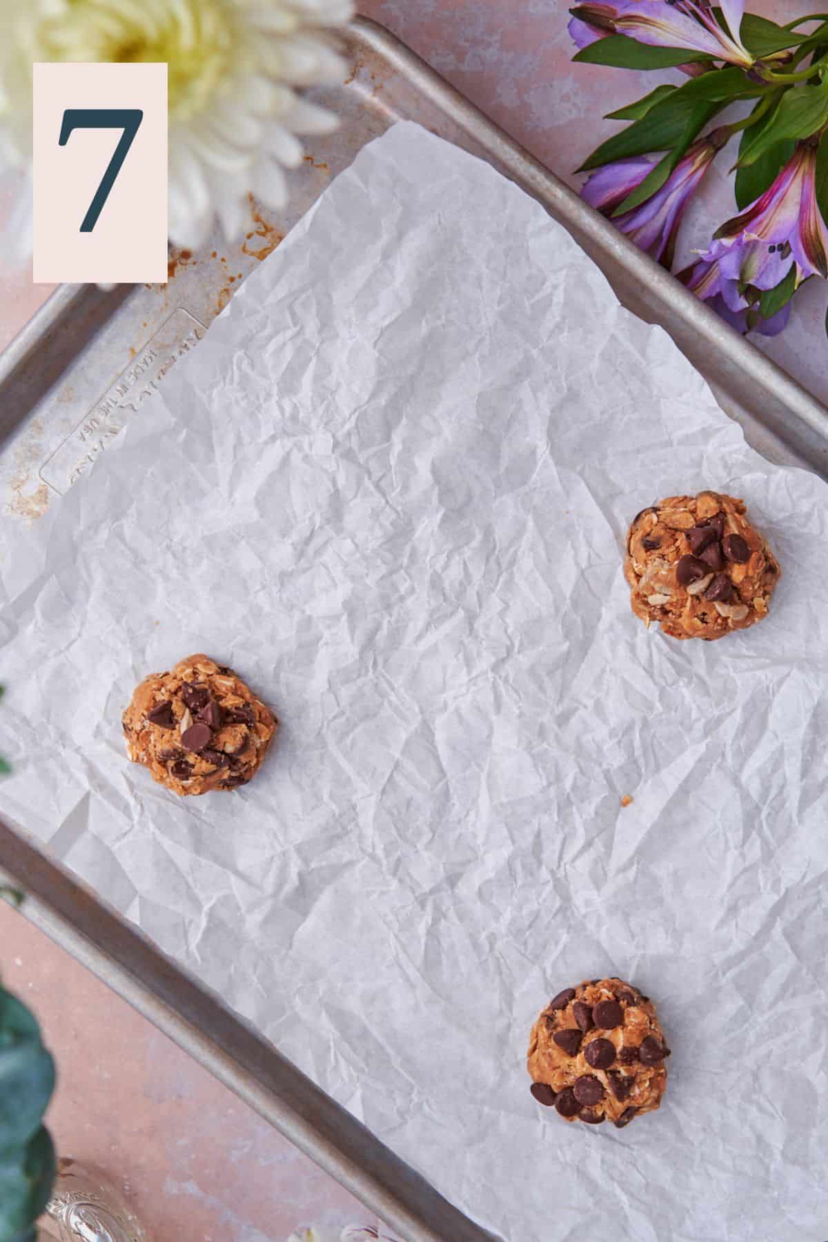 cookie dough rolled into balls with only 3 on a large baking sheet with parchment paper. 