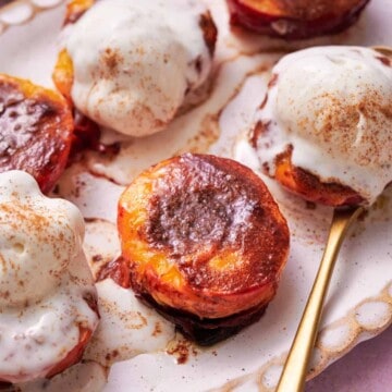 Air fryer peaches topped with ice cream, and a brown sugar cinnamon mixture.
