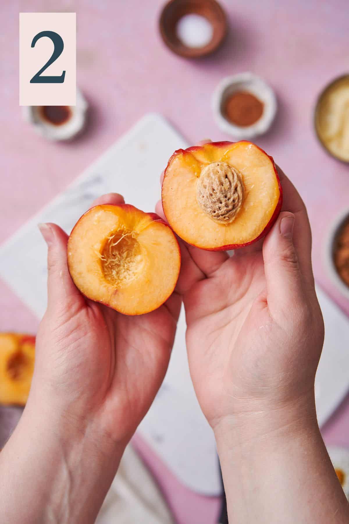 hand showing the inside of a peach to reveal the pit in the middle. 