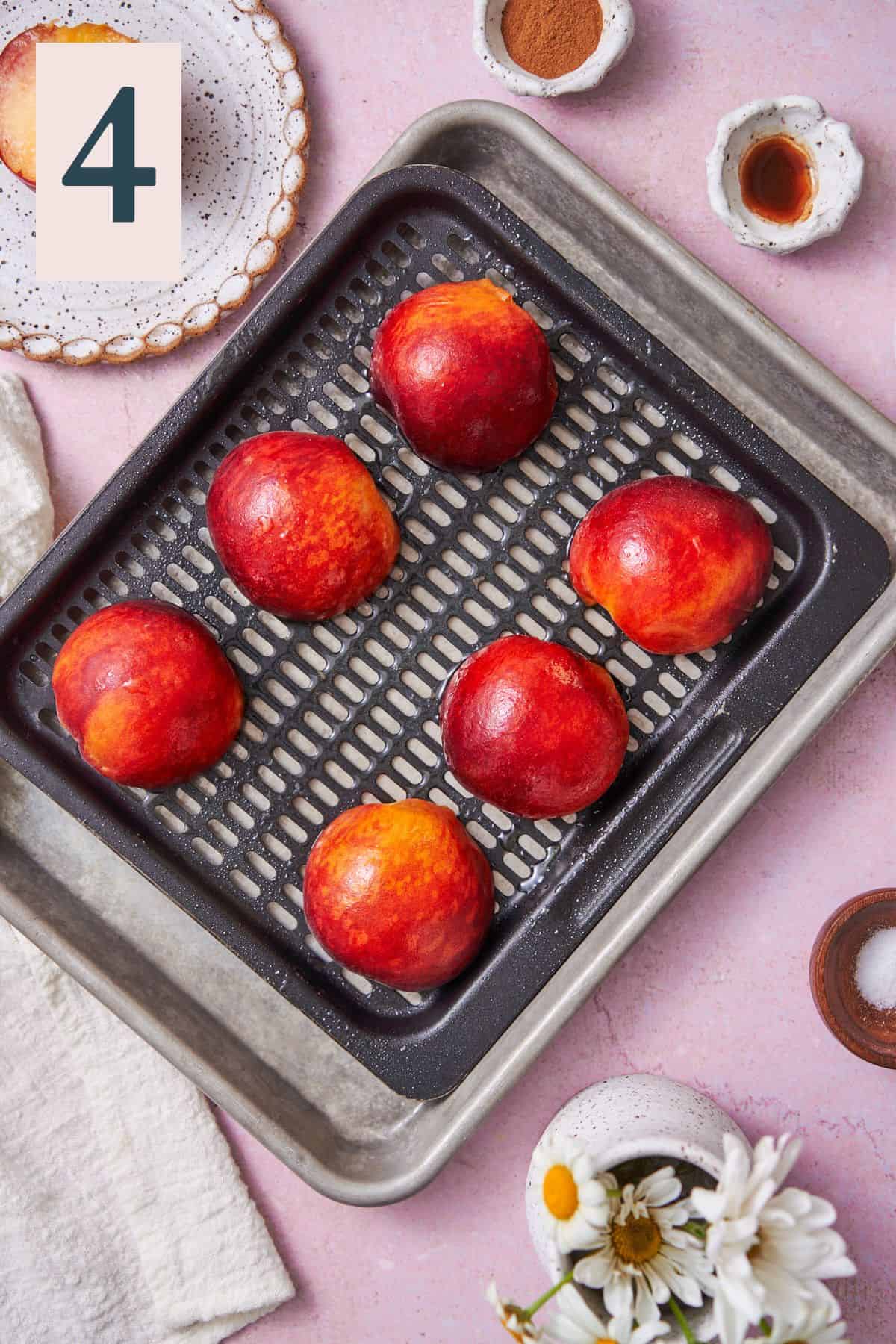 peaches with the cut side down on an air fryer tray, sprayed with baking spray. 