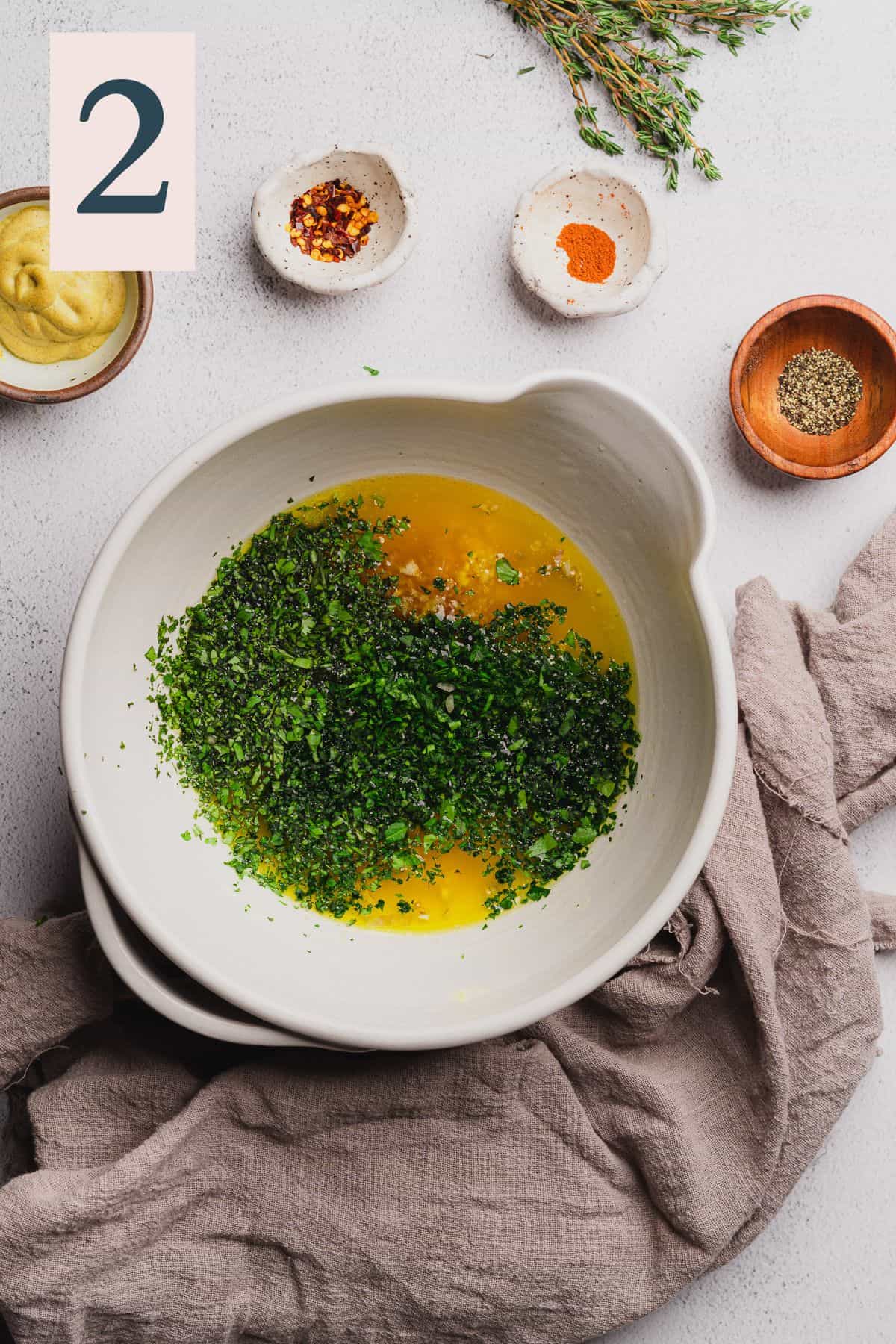 melted butter with parsley, cilantro, chives, and thyme in a bowl.