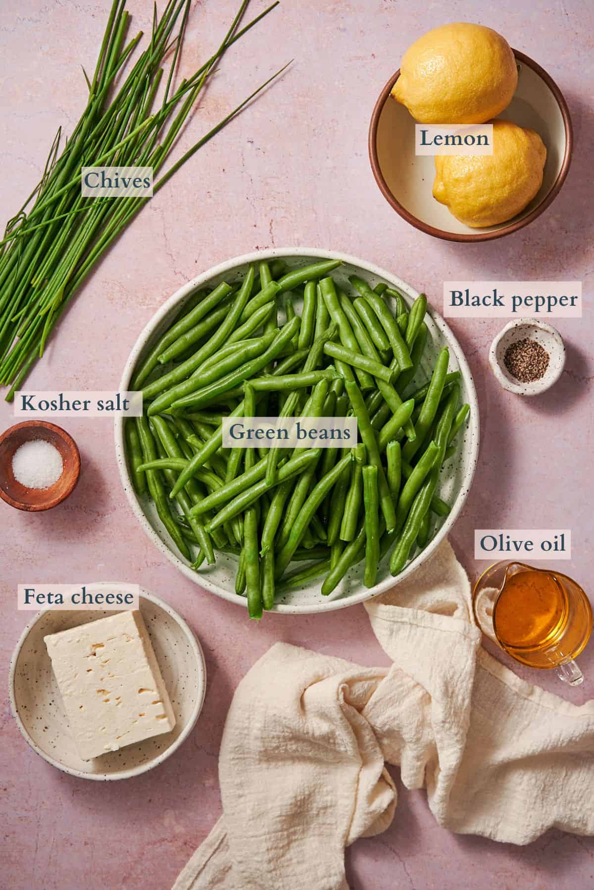ingredients to make a green bean, feta salad laid out in bowls and labeled to denote each ingredient. 