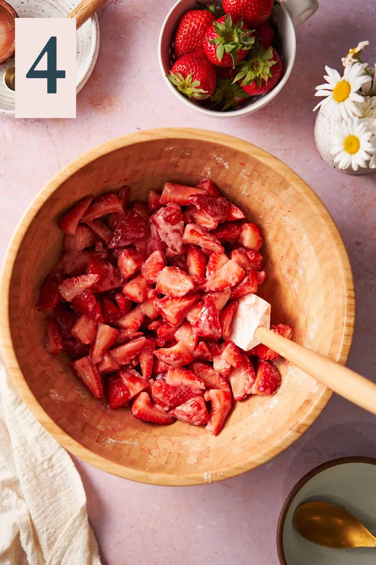 fresh strawberries in a large mixing bowl tossed with flour and other ingredients. 