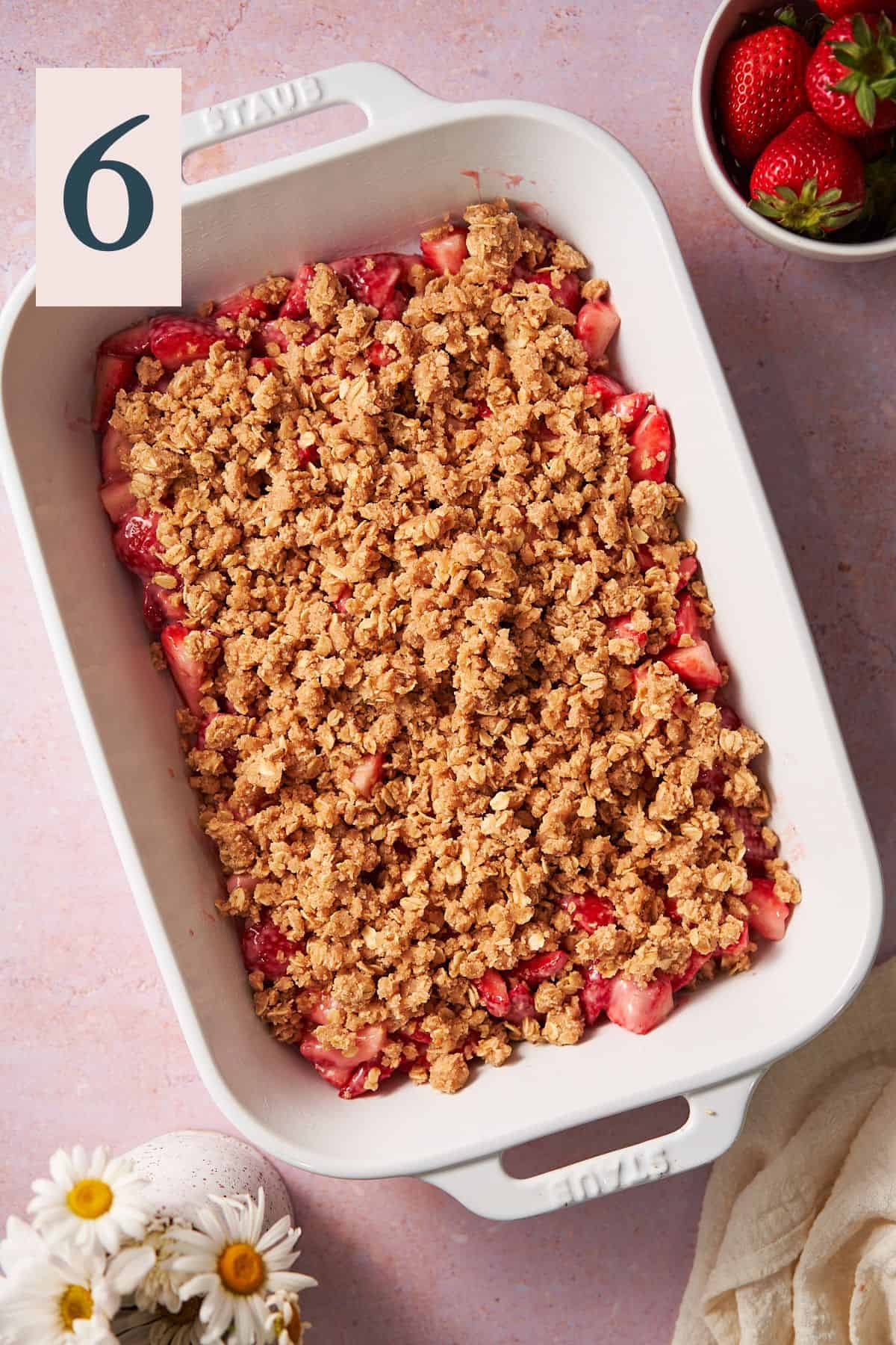 strawberries in a baking dish topped with a buttery crumble topping. 