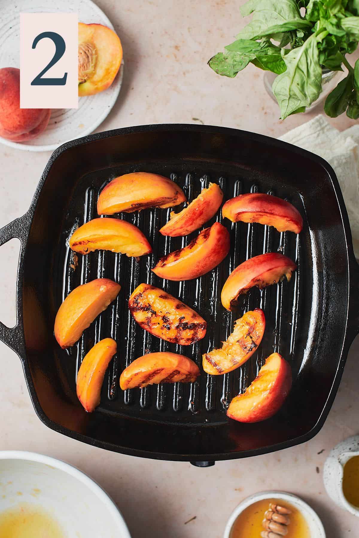Grilling peaches on a hot griddle pan to achieve grill marks.