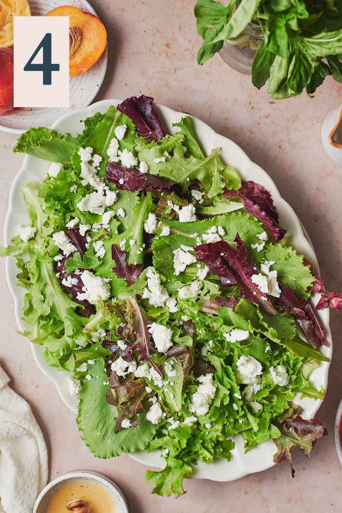 Mixed greens and crumbled feta layered on a scalloped plate.