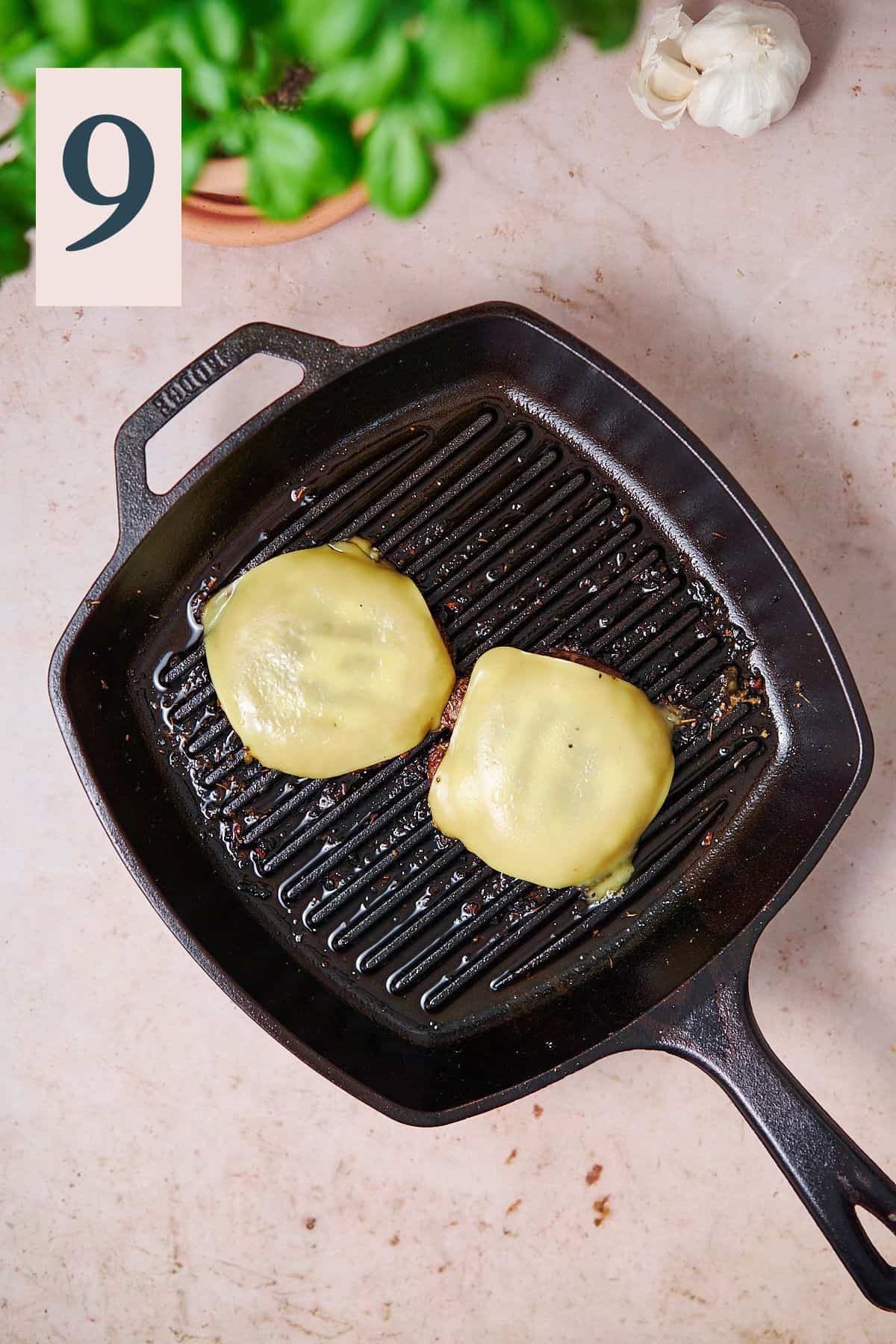 Portobello mushrooms covered with melted cheese on a grill pan. 
