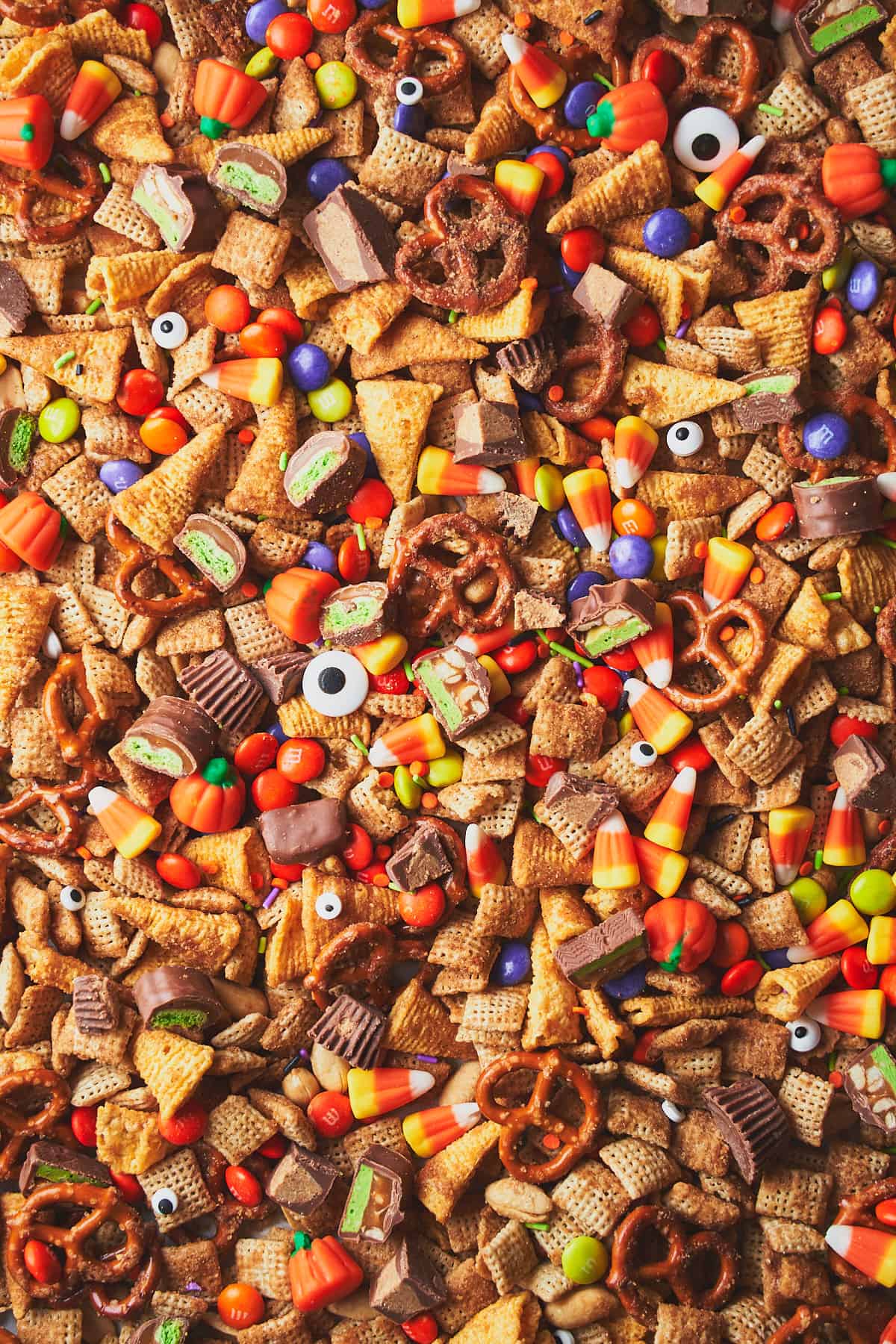 Large tray of Halloween snack mix with Googly eyes, sprinkles, candy corn, candy pumpkins, and chocolate candy bar pieces. 