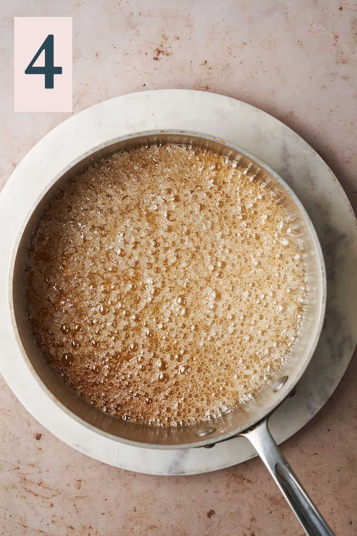 bubbly water and sugar in a sauce pan turning a golden amber color.