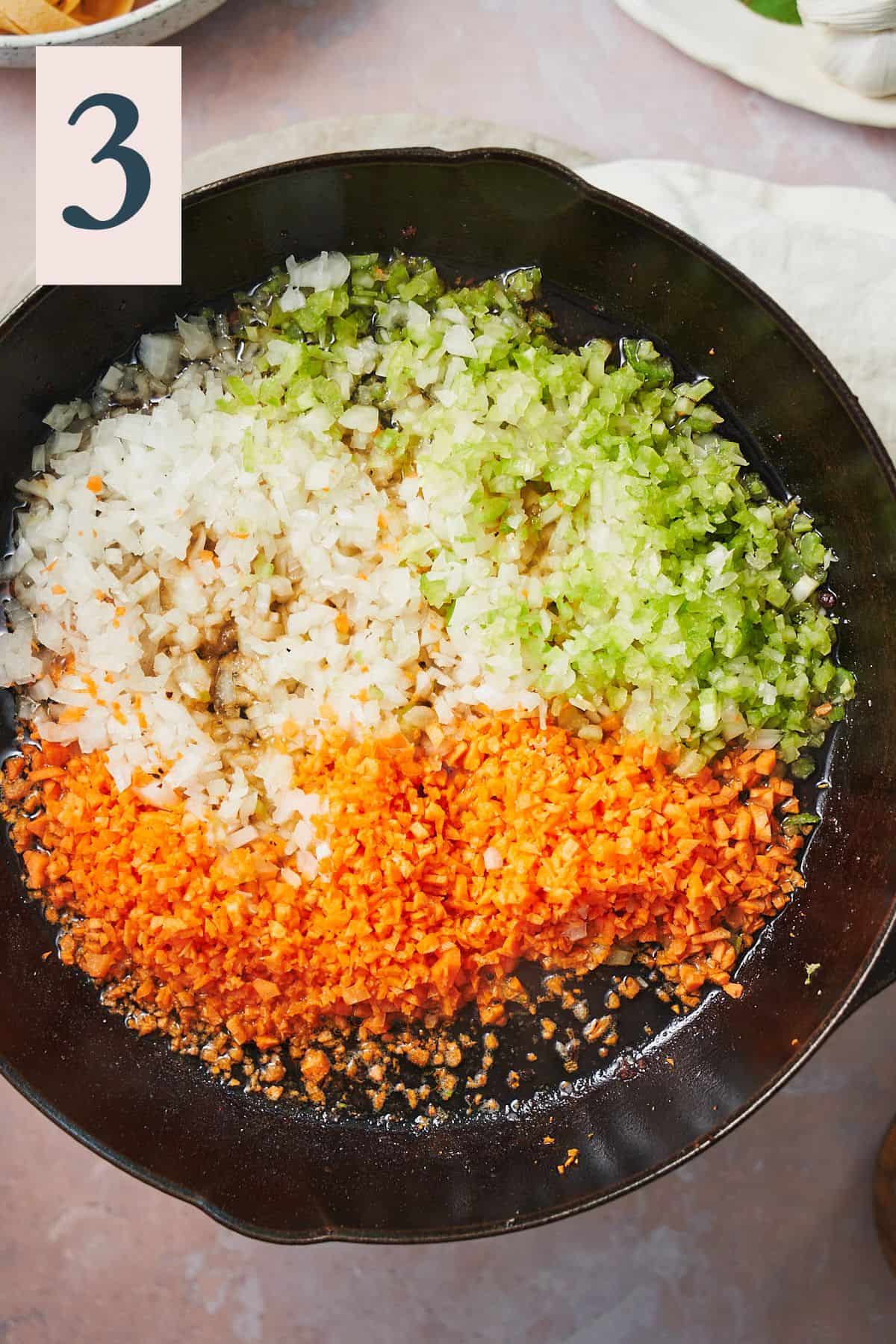 Raw carrots, celery, and and onions in cast iron skillet. 