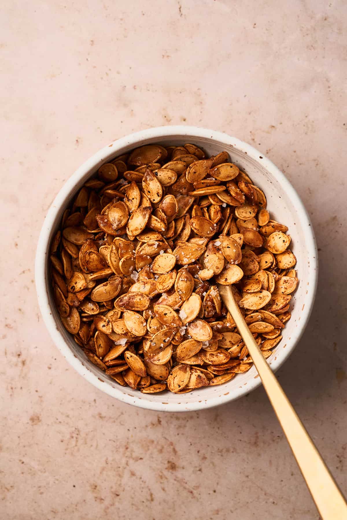Fully roasted pumpkin seeds in a ceramic bowl.