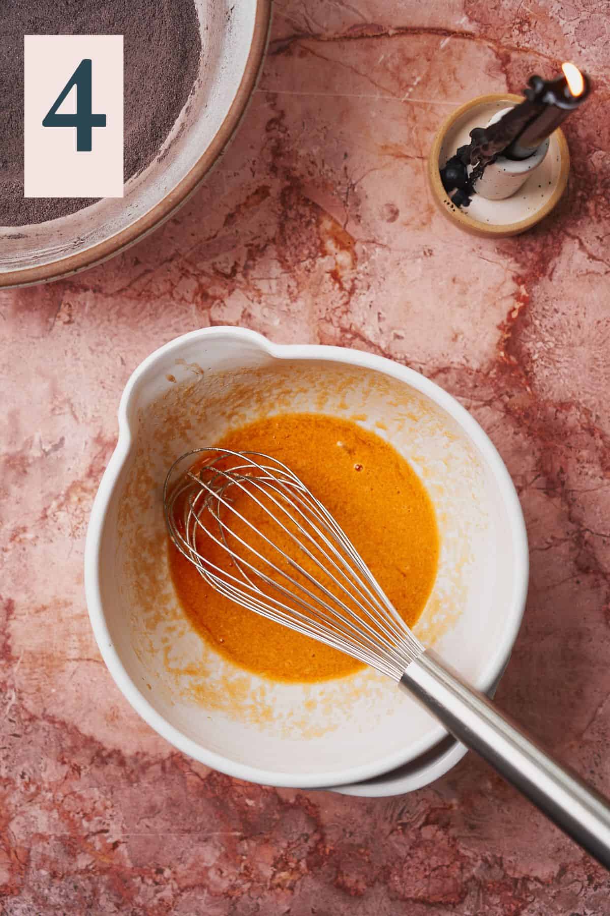 whisked orange liquid to make cupcakes in a bowl. 