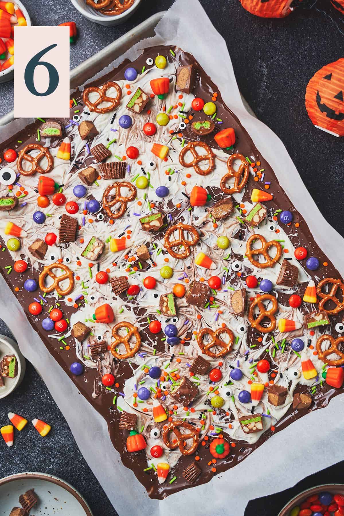 Super cute and spooky halloween chocolate bark with pretzels, sprinkles, and candy all over the top of it. 