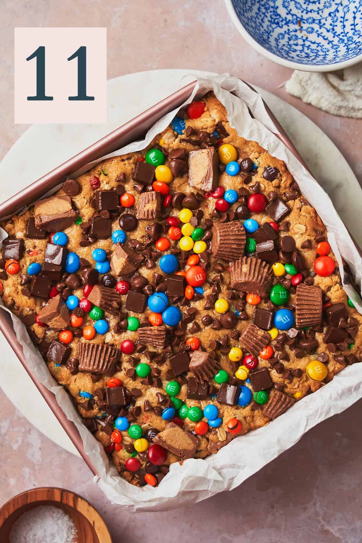 Baked monster cookie bars in a pan with m&ms, reese's, and chocolate chunks. 