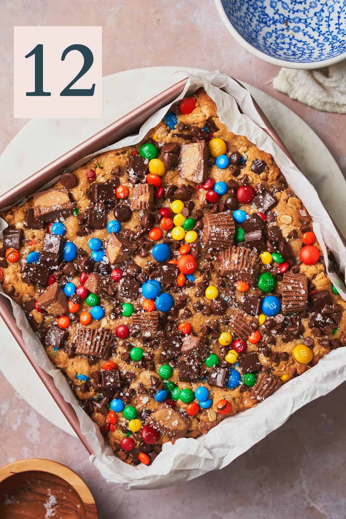 Baked monster cookie bars in a pan topped with flaky sea salt. 