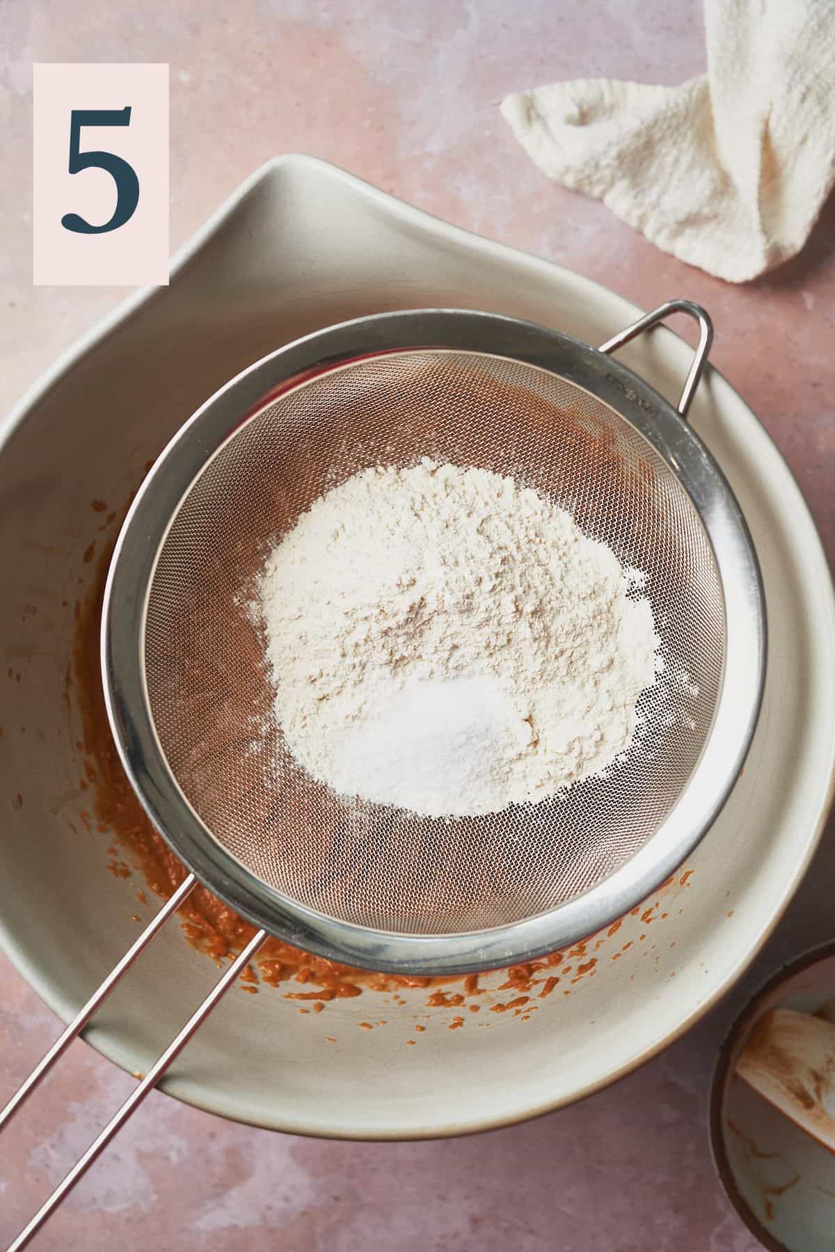 sifting flour, salt, and baking soda into a mixture with a metal sieve.