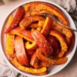 roasted pumpkin wedges, seasoned and prepared on a round ceramic plate.