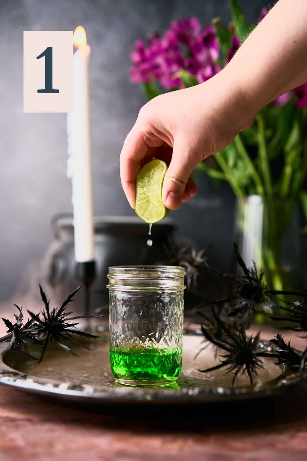hand squeezing lime juice into a mason jar with midori inside. 